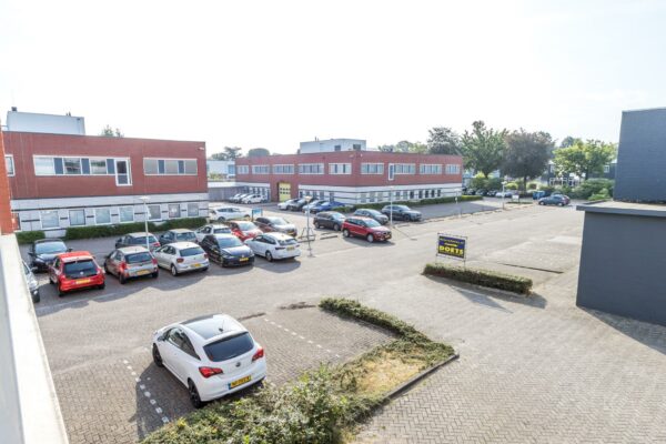 Bedrijventerrein aan de Jan van Eycklaan met geparkeerde auto's en een bedrijfspand met een bord van Doets.